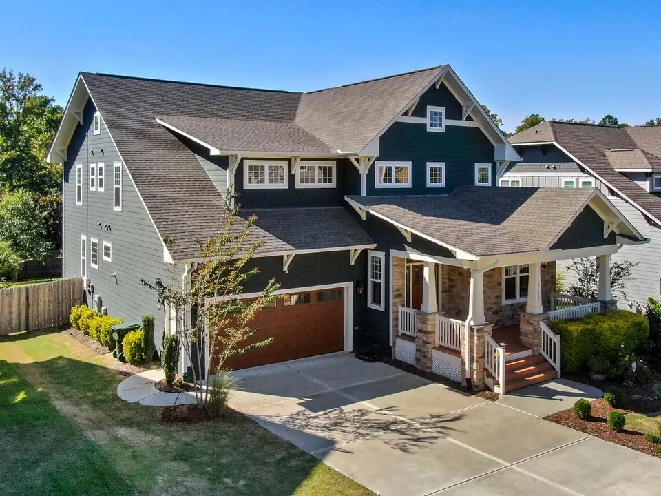 Two-story craftsman home with dark siding and crisp white vinyl windows