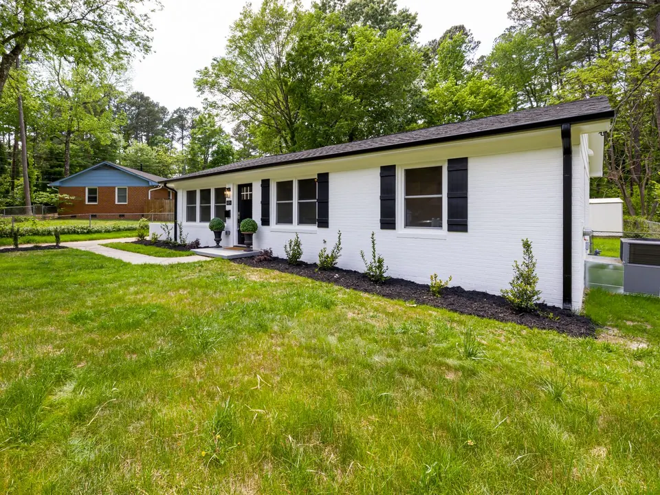 Updated single-story ranch home with black-framed windows and shutters