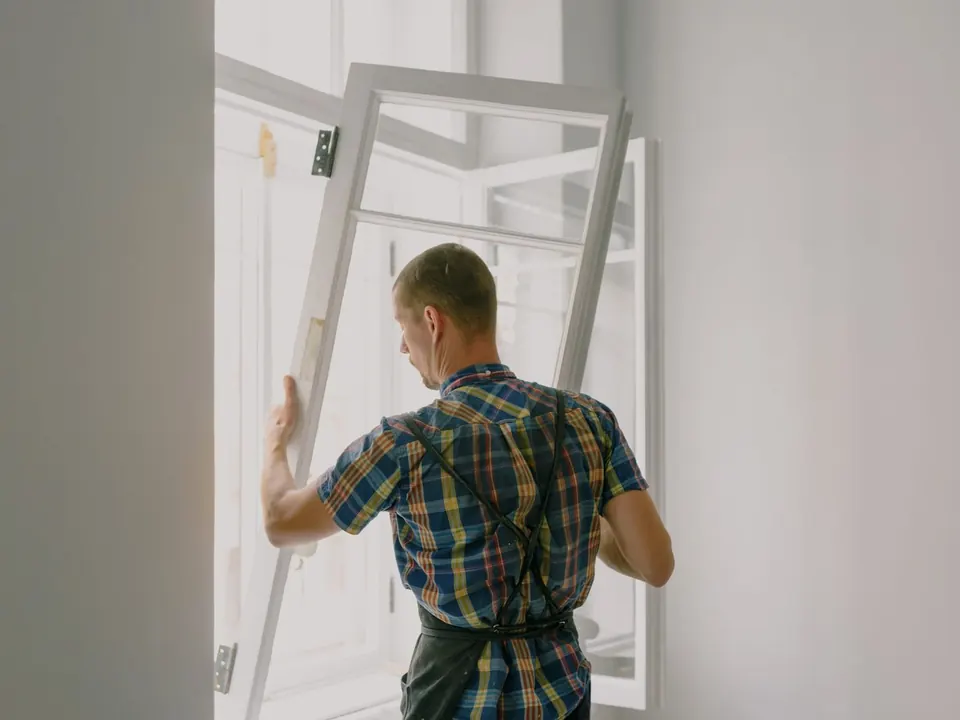 Installer fitting a new white window frame into an opening